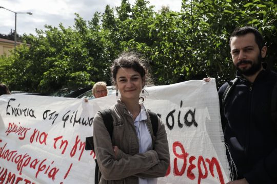 Η δημοσιογράφος Σταυρούλα Πουλημένη μπροστά σε πανό υποστήριξης